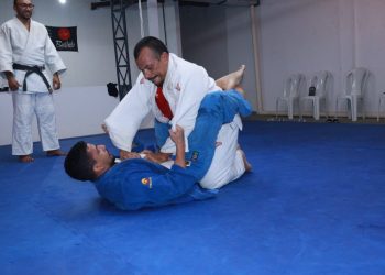Atleta vestindo um kimono branco, aplica um golpe enquanto está por cima de seu oponente, que veste um kimono azul e está de costas sob o tatame - Foto: Divulgação