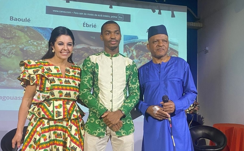 Márcia Santos, Relações Públicas da Costa do Marfim no Brasil; e Noel Hubert Mekan, CEO do Grupo Oasis (Ambos cerimonialistas) recebem ao palco, o palestrante Yayá Touré (Ao centro), Presidente da Associação Marfinense no Brasil – Foto: Divulgação